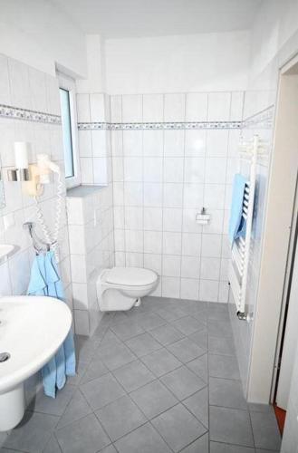 a white bathroom with a toilet and a sink at Studiozimmer-12 in Borkum