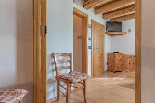 a room with a wooden chair and a kitchen at Chalet Musiera in Telve