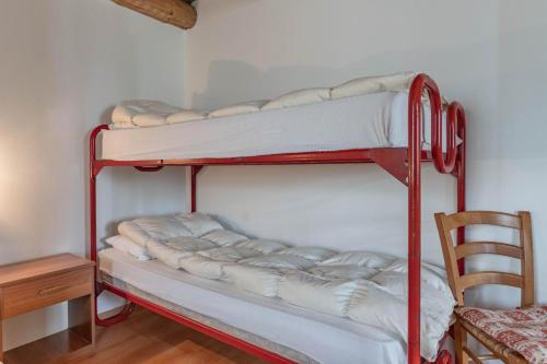 two bunk beds in a room with a chair at Chalet Musiera in Telve
