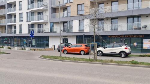 zwei Autos auf einem Parkplatz vor einem Gebäude geparkt in der Unterkunft Apartament Sea & Sun Letnica in Danzig