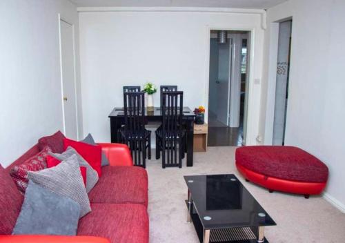 a living room with a red couch and a table at Contractor Accommodation in Crawley Free Parking WiFi Near Worksites Gatwick Manor Royal 2-Bed Sleeps 4 in Crawley