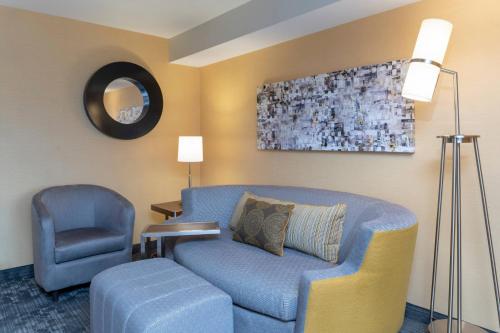 a living room with a blue couch and a chair at Courtyard Milwaukee Airport in Milwaukee