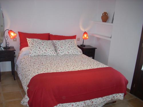 a bedroom with a bed with red pillows and two lamps at La Venta del Arriero in Retuerta de Bullaque