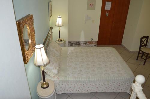 a bedroom with a bed and a mirror and a lamp at Antouanetta Apartments in Ermoupoli