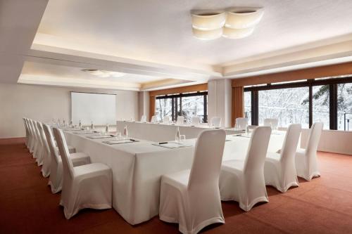a large room with a long table and white chairs at Courtyard by Marriott Hakuba in Hakuba