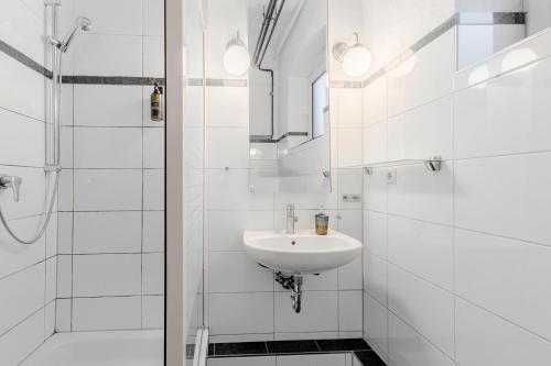 a white bathroom with a sink and a shower at 125qm Loft nahe Stadt und Hafen in Hamburg
