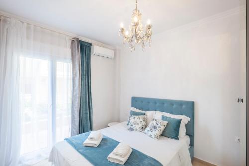 a bedroom with a bed with a blue headboard and a chandelier at Icon Deluxe accommodation in Pefkochori