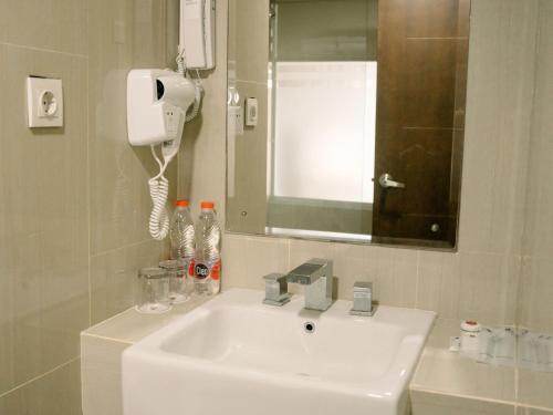 a bathroom with a white sink and a mirror at Merapi Merbabu Hotels Bekasi in Bekasi