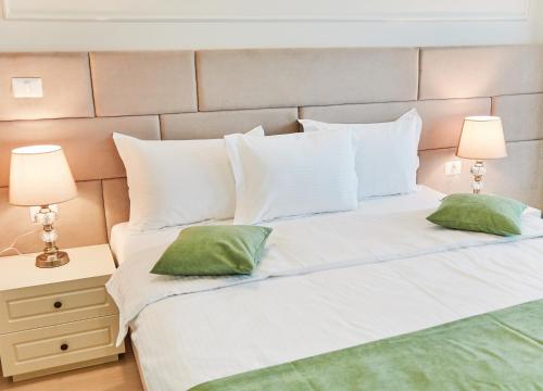 a white bed with two green pillows on it at Hotel Azaleea Mamaia Nord in Mamaia Nord