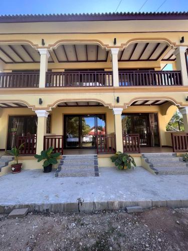 a large yellow building with stairs in front of it at Lebijou Guesthouse - Konesavath in Don Det