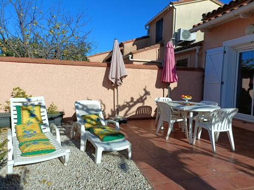 eine Terrasse mit einem Tisch, Stühlen und Sonnenschirmen in der Unterkunft VILLA CITRONNELLE Grande maison 2 chambres avec jardin proche plage - Clim - Wifi in Saint Cyprien Plage
