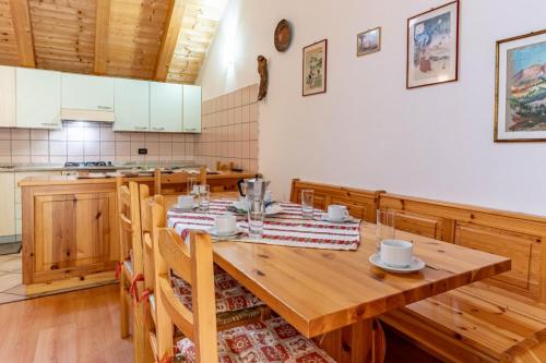 a dining room with a wooden table and a kitchen at Chalet Musiera in Telve