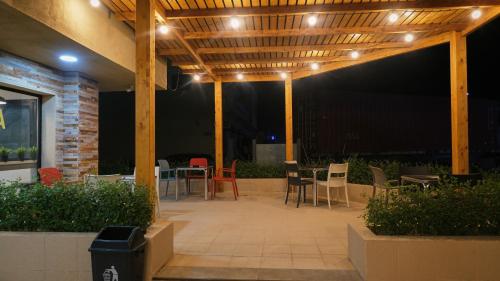 a patio with chairs and tables under a wooden pergola at Hotel Aloe Emira NKC in Nouakchott