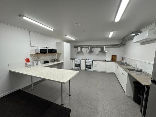 a large kitchen with white cabinets and a table in it at Backpackers Central Hamilton in Hamilton