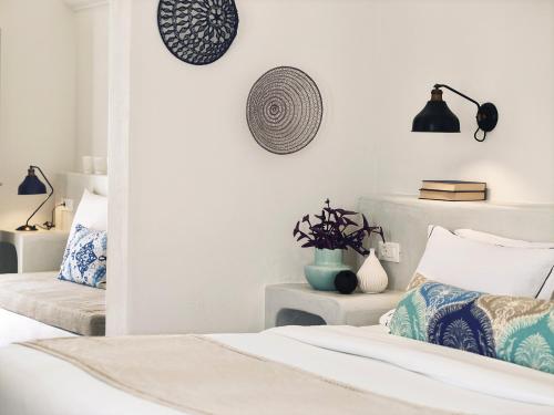 a bedroom with two beds with blue and white pillows at Santo Pure Oia Suites & Villas in Oia