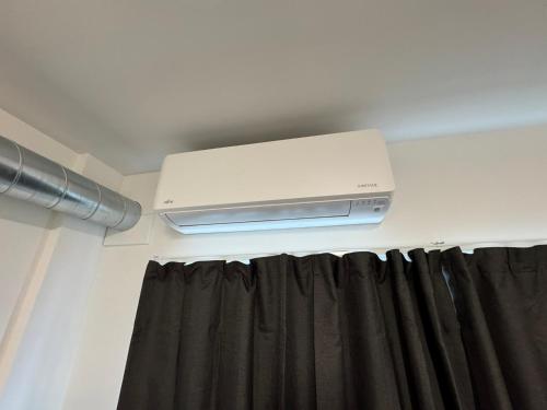 a room with a curtain and a air conditioner at Backpackers Central Hamilton in Hamilton