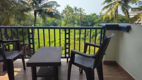 a balcony with chairs and a table and a view at Beach Bliss Apartment Hotel - 7 Minutes walk to Beach in Colva