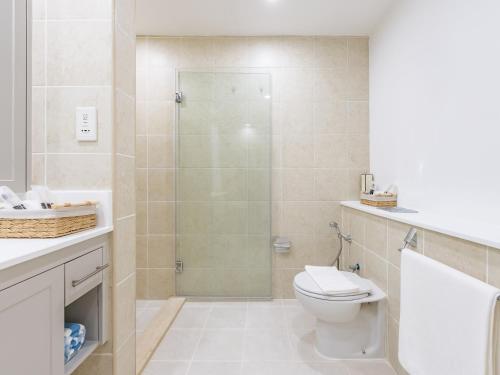 a bathroom with a toilet and a glass shower at the Byron Bay condo in Dubai