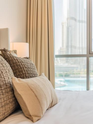 a bed with pillows and a window with a view at the Byron Bay condo in Dubai