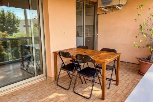 une table en bois avec quatre chaises devant une fenêtre dans l'établissement Carla - vue mer clim wifi parking - by TGB, à Ajaccio