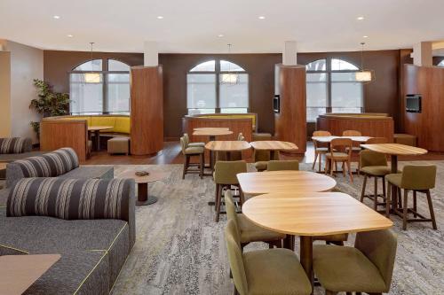 a restaurant with wooden tables and chairs and windows at Courtyard by Marriott Houma in Houma