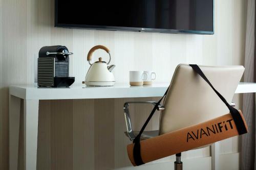 a desk with a tea kettle and a chair at Avani Frankfurt City Hotel in Frankfurt/Main