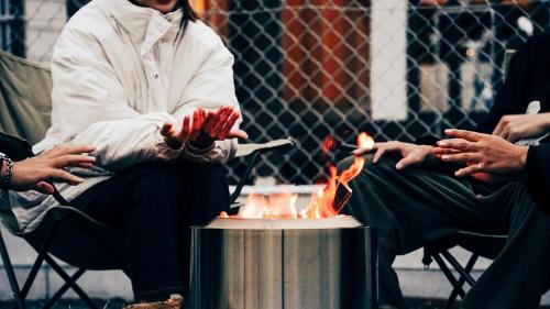 a group of people sitting around a fire pit at 海まで徒歩5分-BBQ バレルサウナ ジャグジー ペットOKの貸切villa in Ichinomiya
