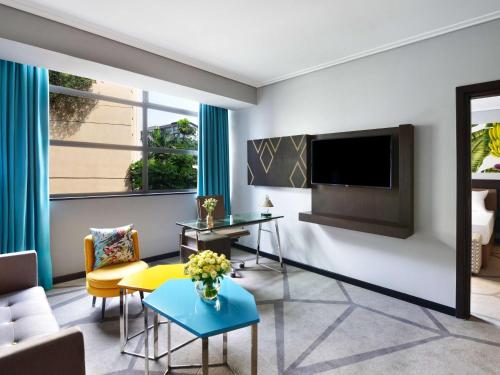 a living room with a couch and a tv at Novotel Nairobi Westlands in Nairobi