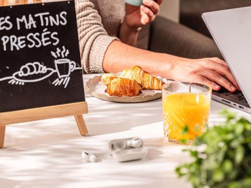 a person sitting at a table with a laptop and a plate of food at Novotel Nairobi Westlands in Nairobi