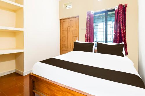a bedroom with a large white bed and a window at Hotel O Khushi Guest House in Bhubaneshwar