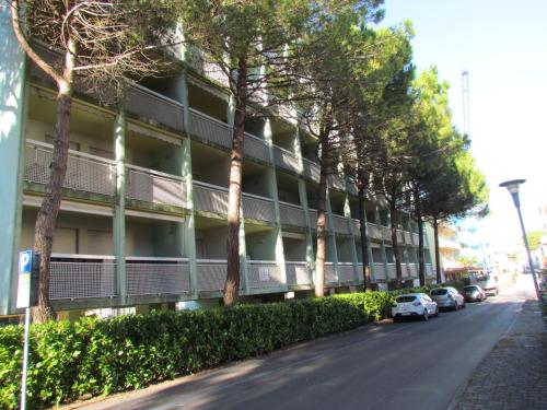 Un edificio de apartamentos con coches aparcados delante. en Condominio Athena, en Bibione