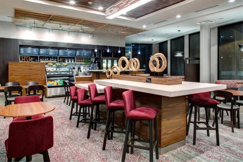 a restaurant with a bar with red chairs and tables at Courtyard by Marriott Nashville Mount Juliet in Mount Juliet