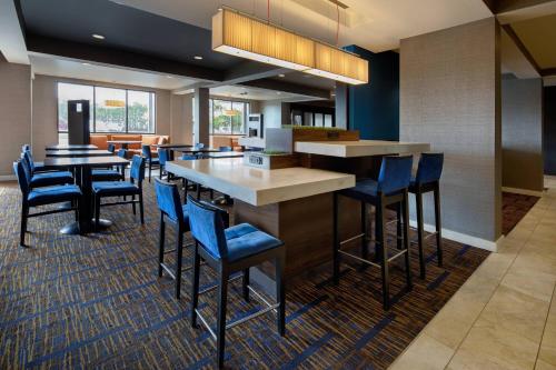 a restaurant with blue chairs and a large bar at Courtyard Grand Rapids Airport in Grand Rapids