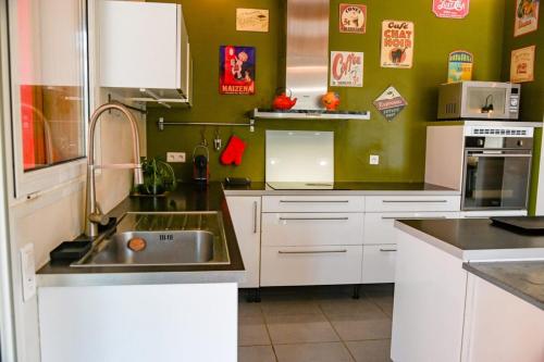 La cuisine est équipée de placards blancs et d'un évier en acier inoxydable. dans l'établissement Jardin des Abeilles - Villa Pool Terrace - by TGB, à Ocana