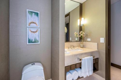 a bathroom with a sink and a toilet and a mirror at Courtyard by Marriott Bogota Airport in Bogotá