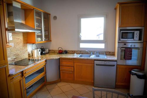 une cuisine avec des armoires en bois, un évier et une fenêtre dans l'établissement Rosella - Rooftop Hypercentre - by TGB, à Ajaccio