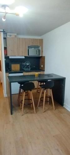 une cuisine avec une table noire, des chaises et un four micro-ondes dans l'établissement Studio à 300M des pistes, à Saint-Jean-dʼAulps