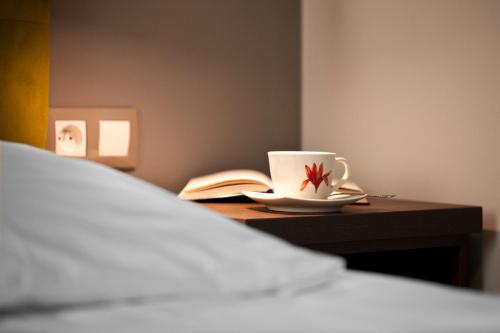 a bed with a cup and a book on a table at Pokoje Gościnne Tessa in Chełm