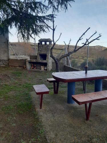 a picnic table and two benches in a field at Casa Rural El Maragato in Navalsauz
