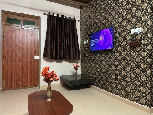 a room with a tv on a wall with a table at Villa De Pondicherry in Puducherry