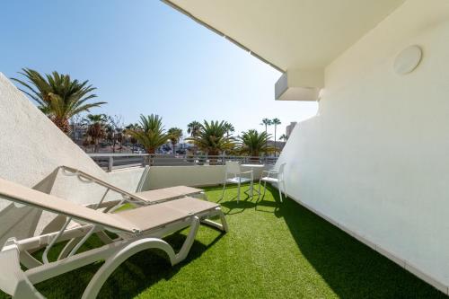 a patio with chairs and grass on a building at Olé Tropical Tenerife Adults Only in Playa de las Americas