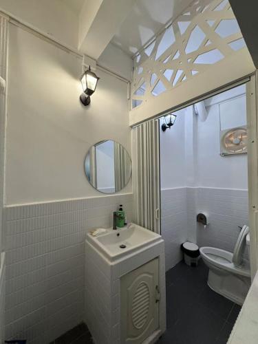 a bathroom with a sink and a toilet and a mirror at The Moment Hostel in Bangkok