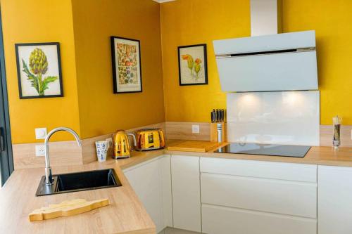 d'une cuisine avec des placards blancs, un évier et des murs jaunes. dans l'établissement Sandrine - Villa Terrace Pool - by TGB, à Pietrosella
