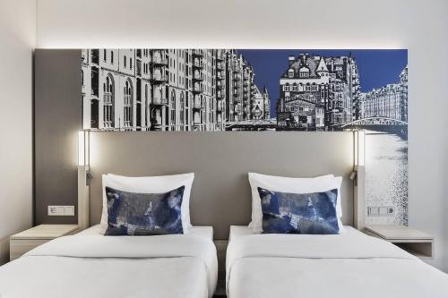 two beds in a room with a painting on the wall at Courtyard by Marriott Hamburg City in Hamburg