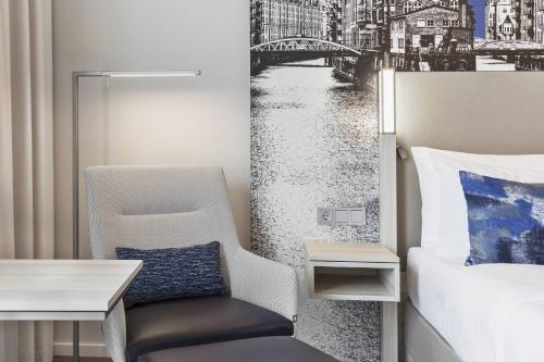 a bedroom with a desk and a chair next to a bed at Courtyard by Marriott Hamburg City in Hamburg