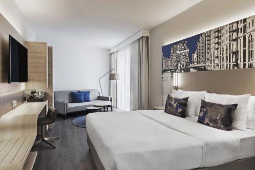 a hotel room with a large bed and a couch at Courtyard by Marriott Hamburg City in Hamburg
