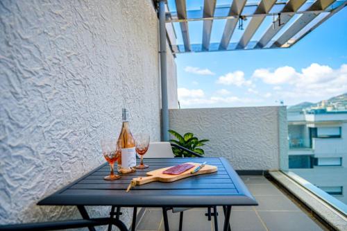 - une table bleue avec 2 verres et une bouteille de vin dans l'établissement Paolina - Terrasse Parking Clim wifi - by TGB, à Ajaccio