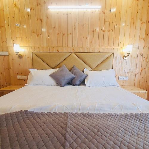a bedroom with a large bed with wooden walls at Ekaant Stays - Manali in Manāli