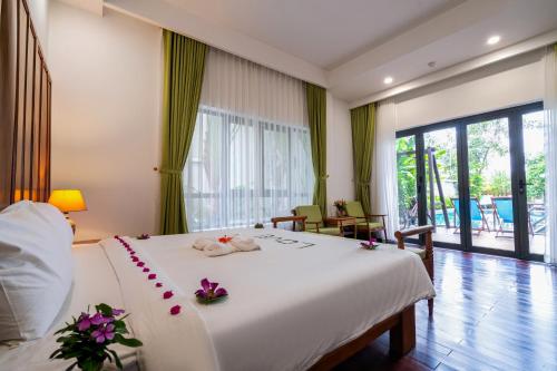 a bedroom with a large white bed with flowers on it at Palm Riverside Boutique in Hoi An