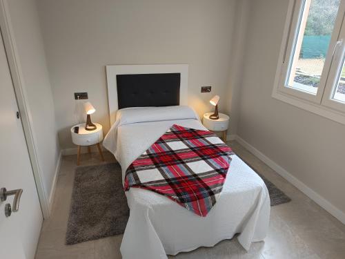 a white bedroom with a bed with a blanket on it at Casa Ponteverde in Coristanco